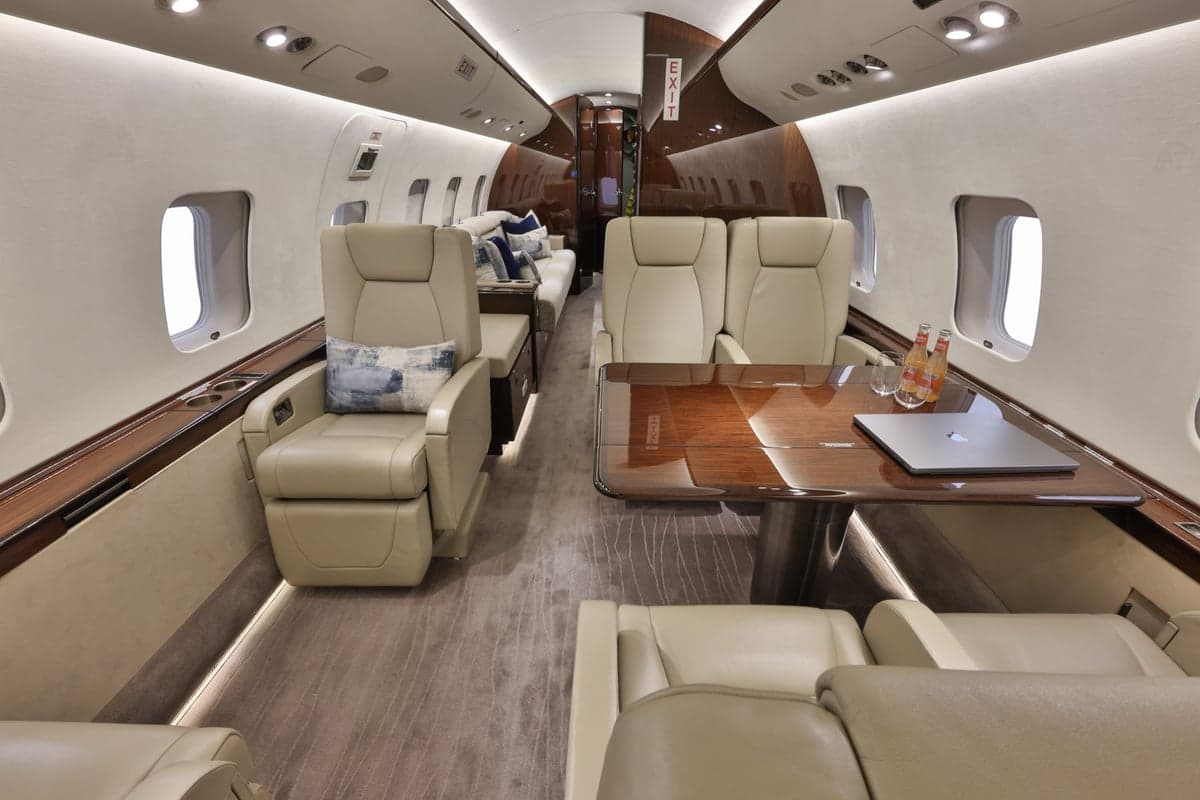 View of the Bombardier Global Express cabin interior with leather seating, a table, and a couch.