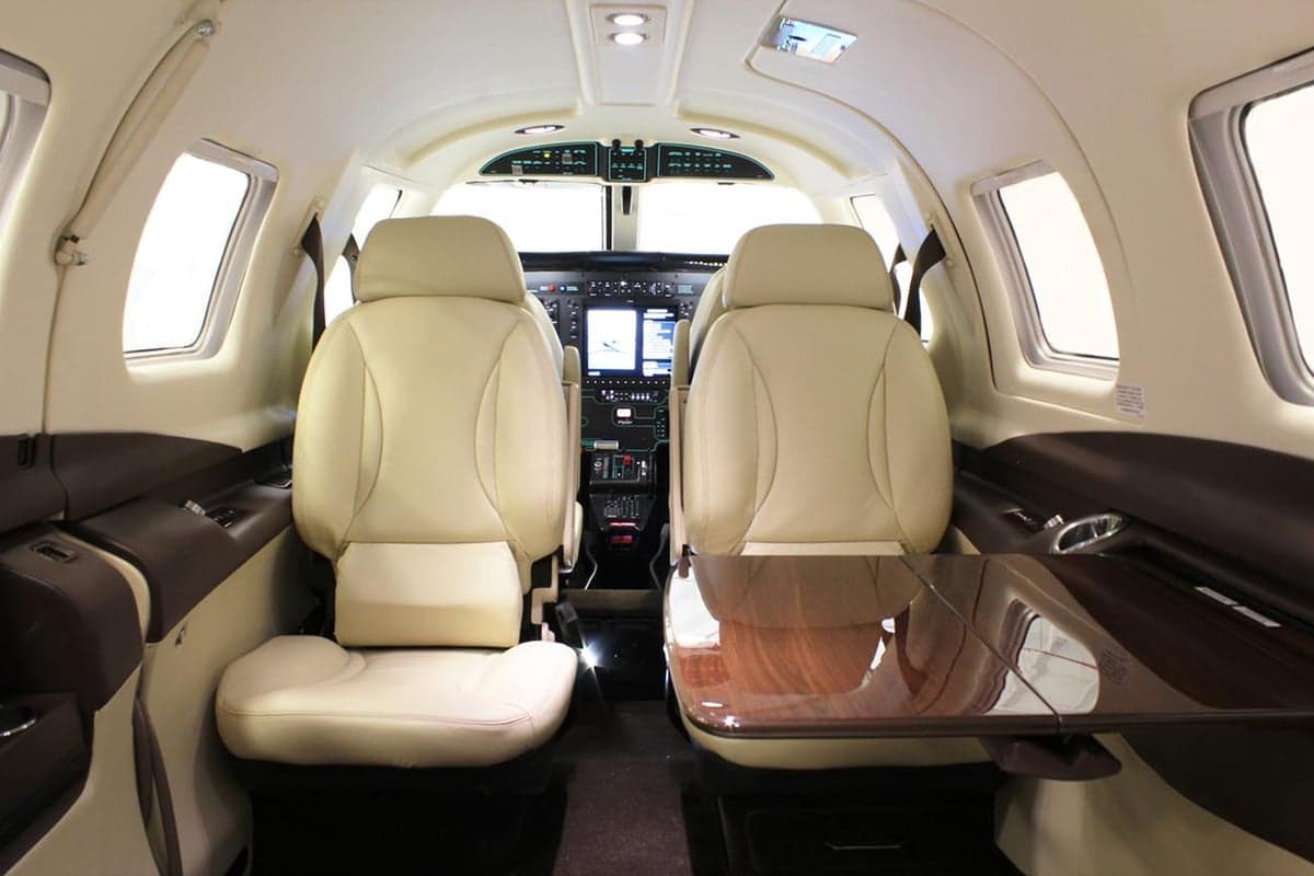 View of the aircraft cabin with leather seats and a table.