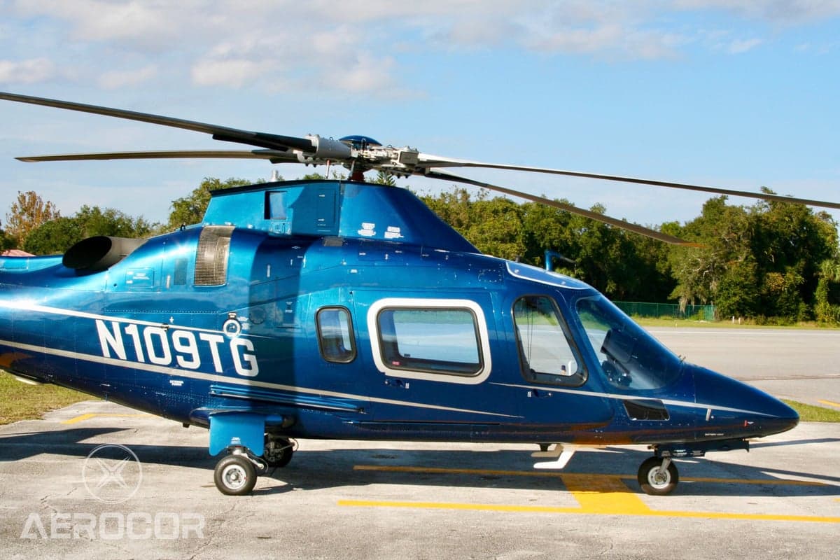 Close-up side view of the main cabin and rotor mast of a blue AgustaWestland AW109 helicopter (N109TG).