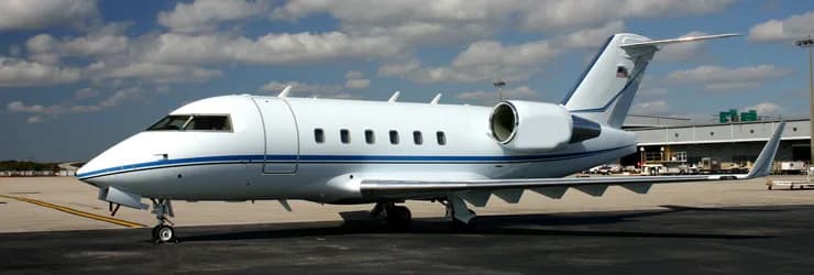 A white jet with blue stripes parked on the tarmac.