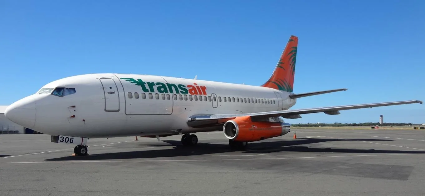 A Transair 737 aircraft is parked on the tarmac.