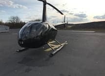 Front quarter view of a black Robinson helicopter on the tarmac.
