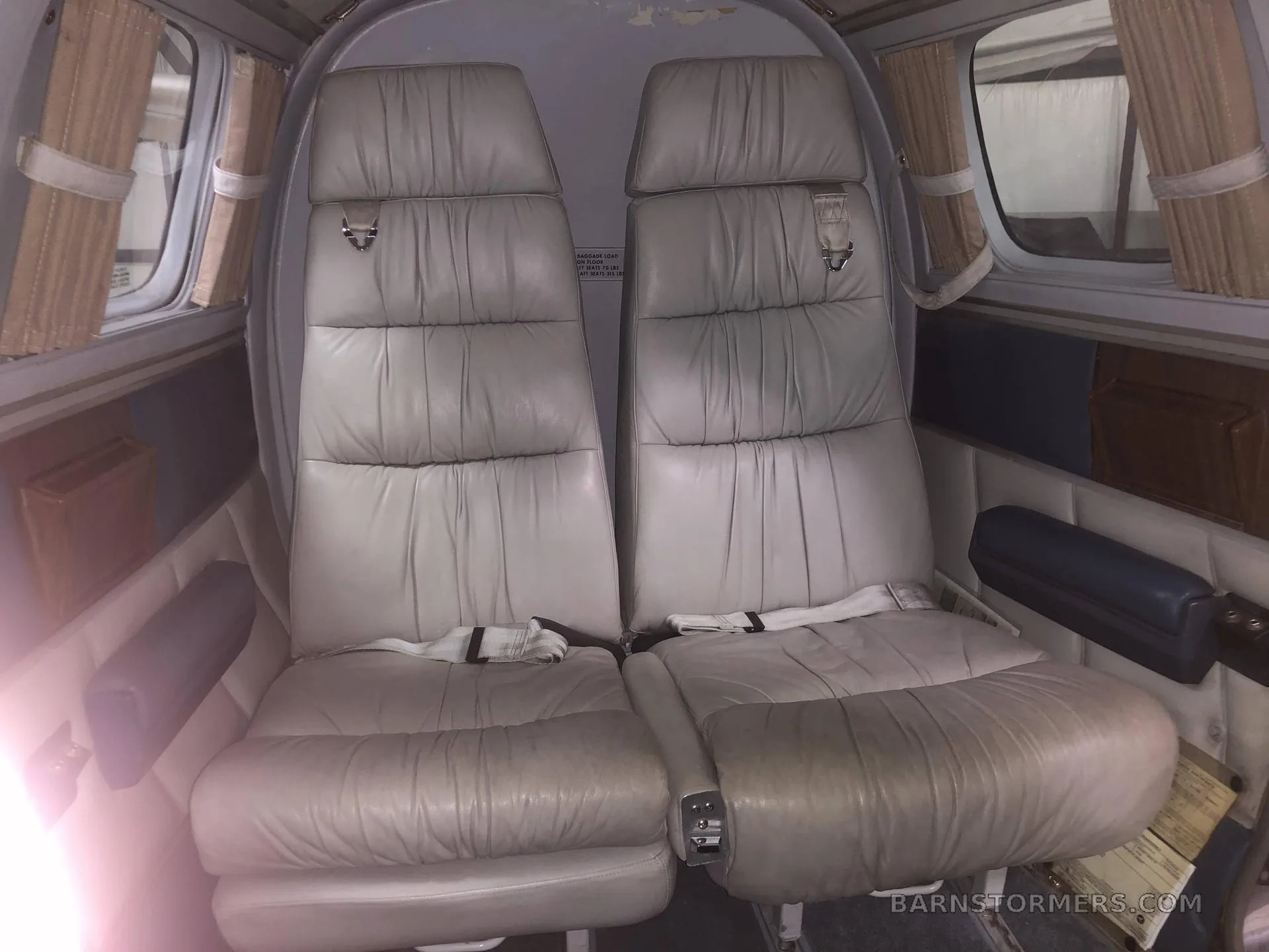 Two rows of light grey leather passenger seats are visible in the aircraft's cabin.