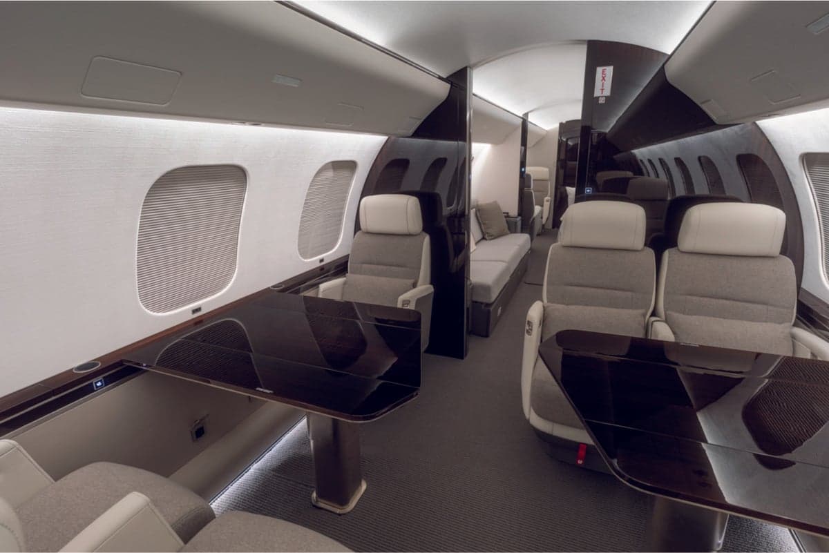 Bombardier aircraft interior with seats and tables.