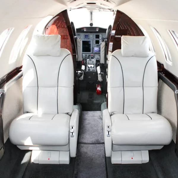 View from the aircraft cabin looking forward into the cockpit, showing two light-colored leather seats.