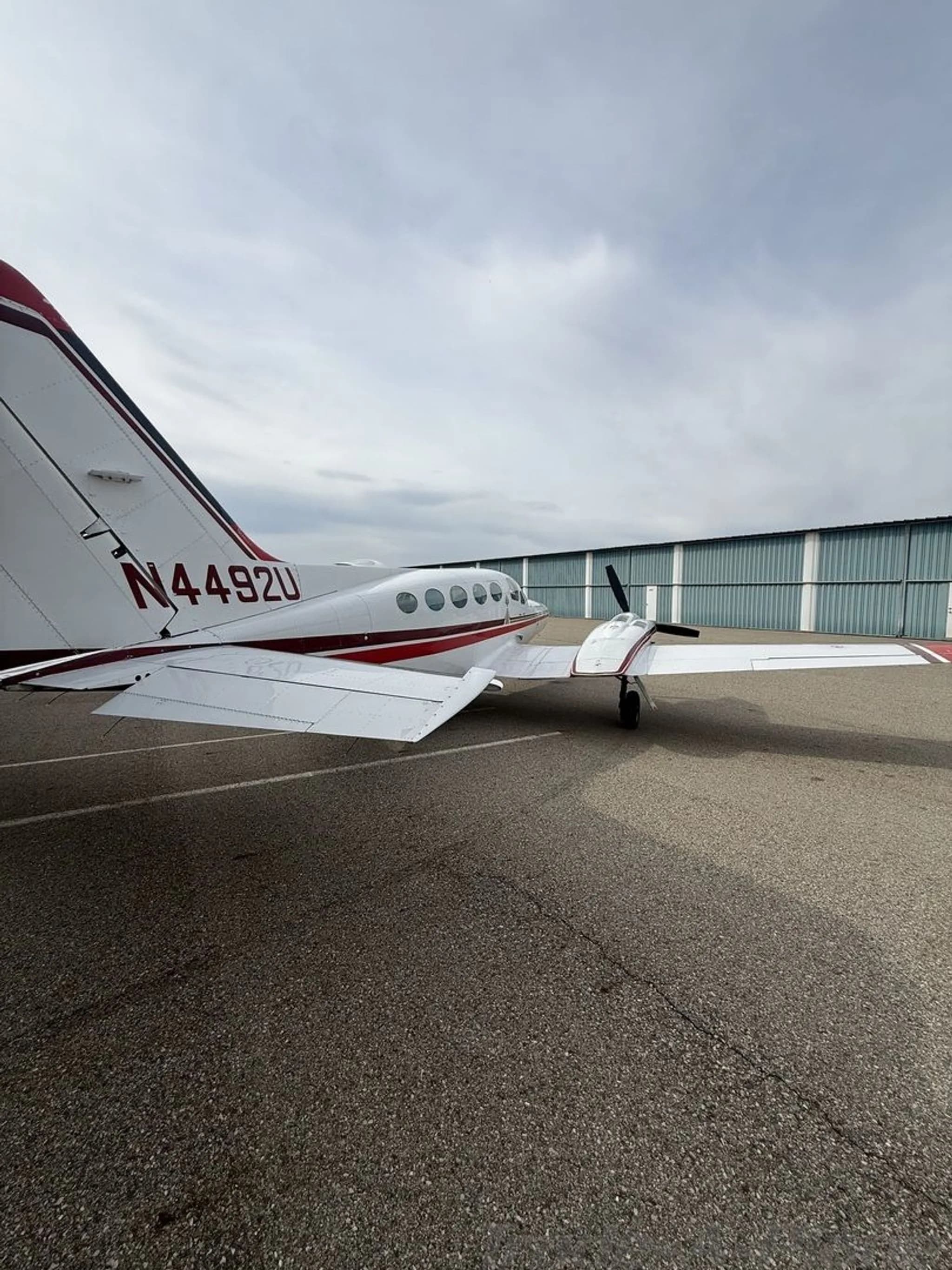 A rear quarter view of a white and red twin-engine Cessna 414 Chancellor aircraft, registration N4492U, parked on an asphalt ramp.