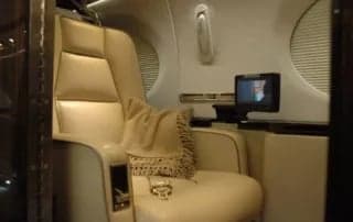 A single seat in the aircraft interior with a small table and monitor.