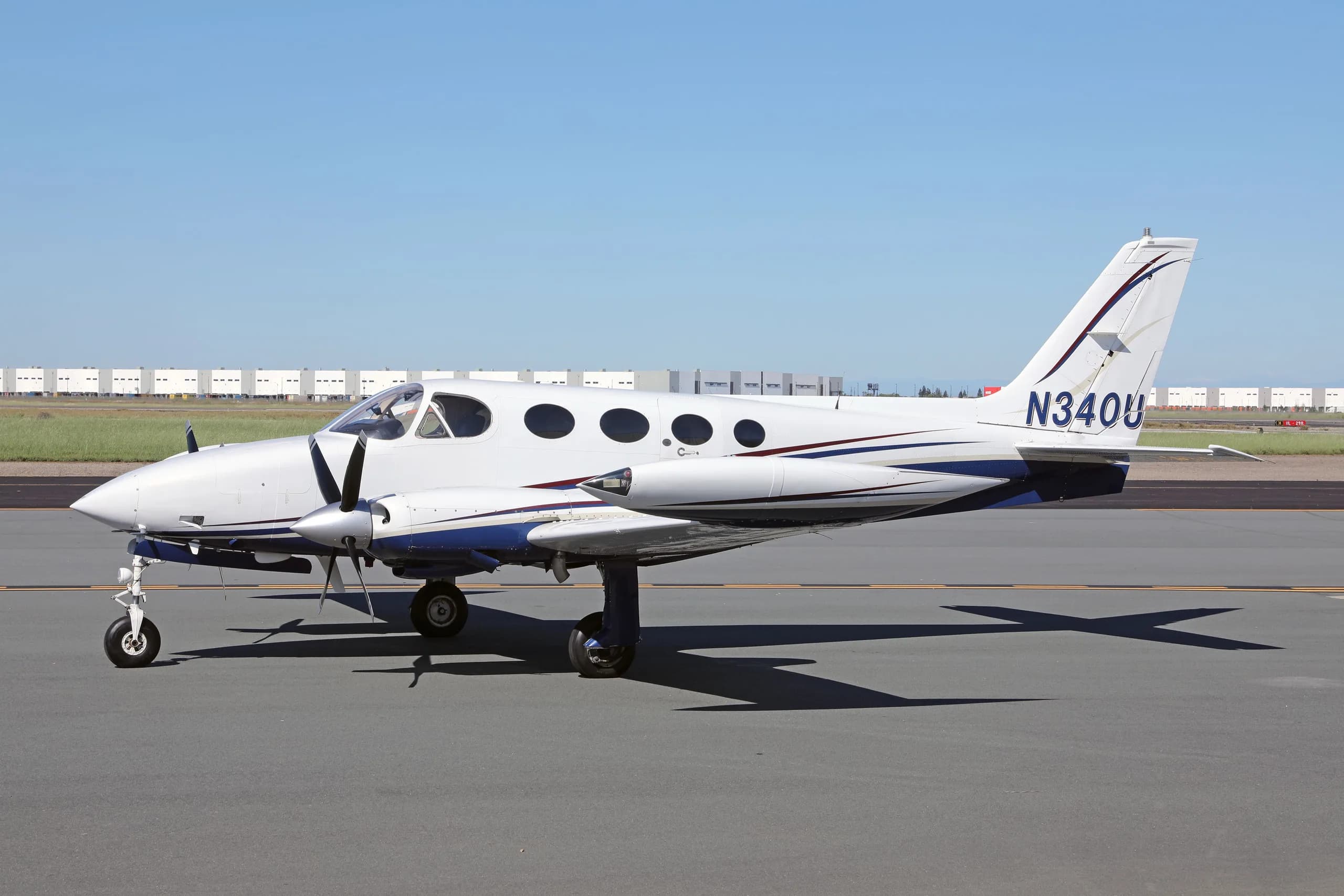 A white and blue Cessna 340 twin-engine aircraft with registration N340U parked on an airfield.