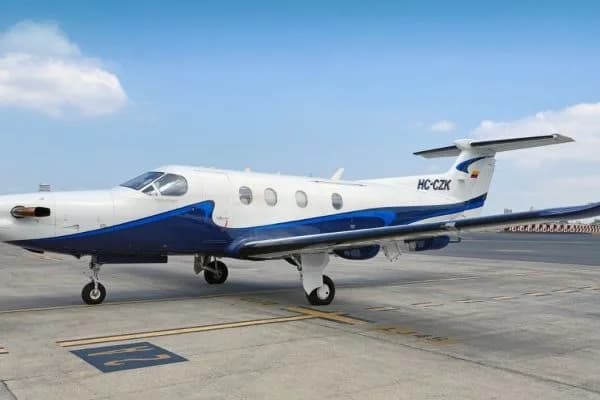 A white and blue Pilatus PC-12 aircraft with registration HC-CZK parked on an airport tarmac.