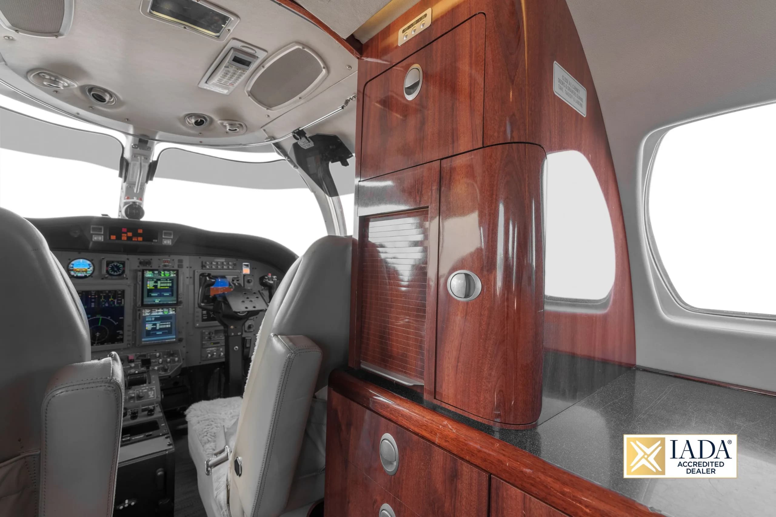 The forward cabin interior of a Cessna Citation business jet, featuring wood cabinetry and a view into the cockpit.