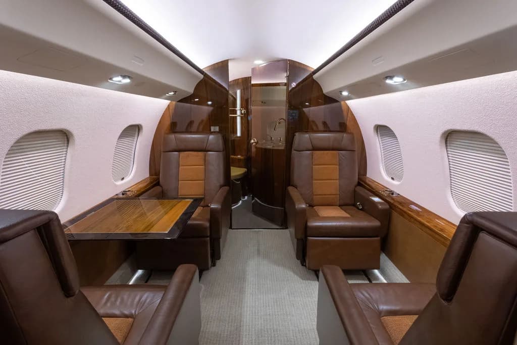 The aircraft's interior features brown leather seats and a table.