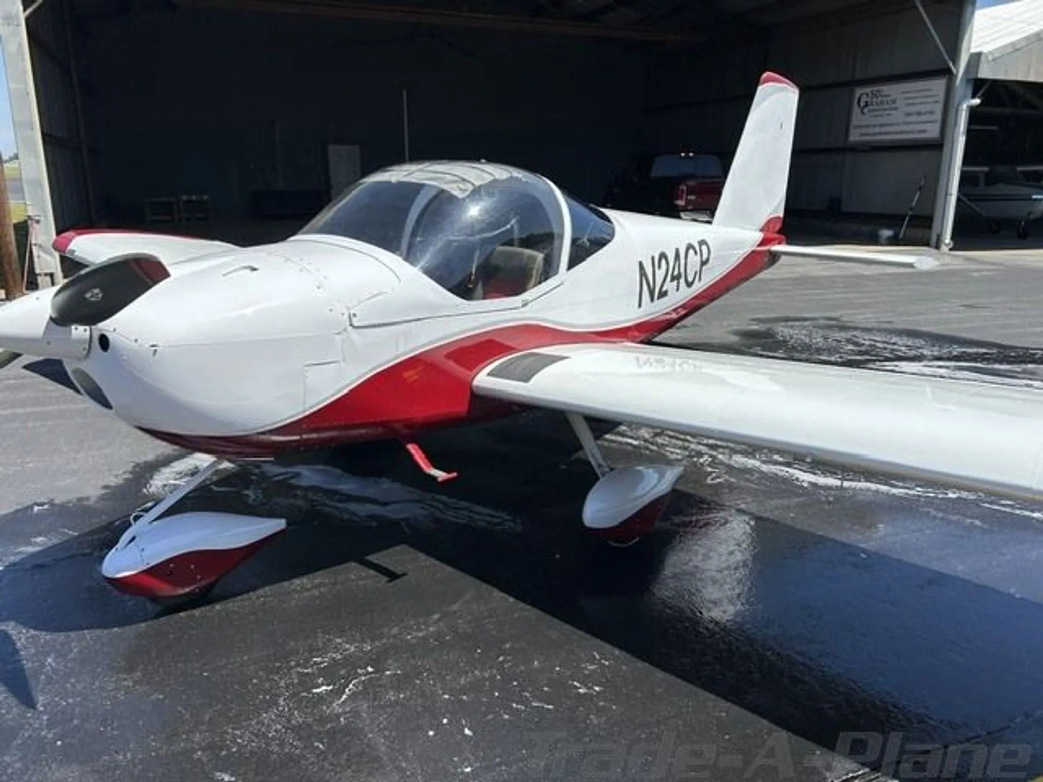 A close-up view of the front-right side of the white and red Van's RV-12 aircraft, N24CP, on a tarmac.