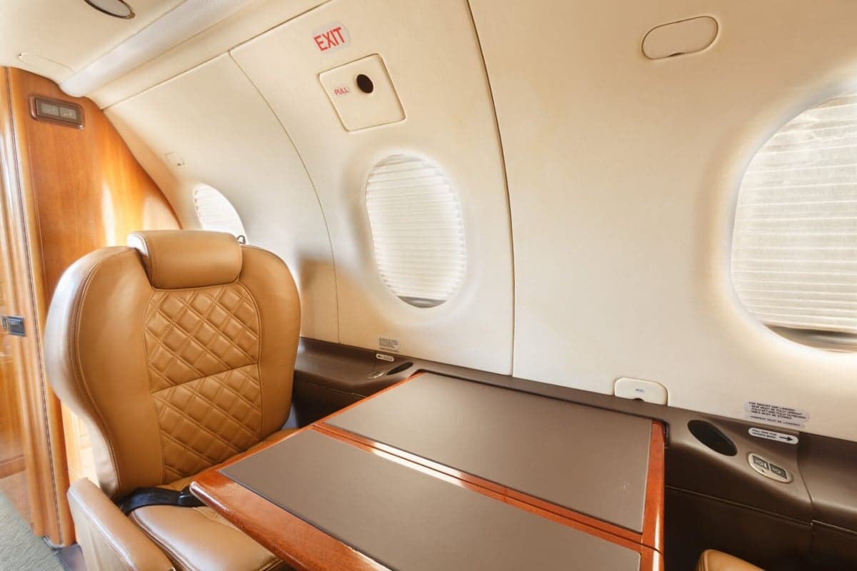 Close-up of a tan leather seat and table inside the aircraft cabin.