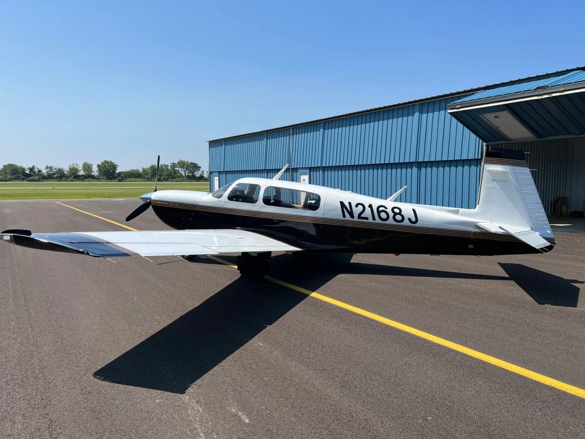 Side view of the N2168J aircraft on the tarmac in front of a hangar.