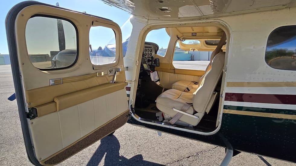 The interior of the aircraft features cream-colored leather seats and a view of the cockpit.