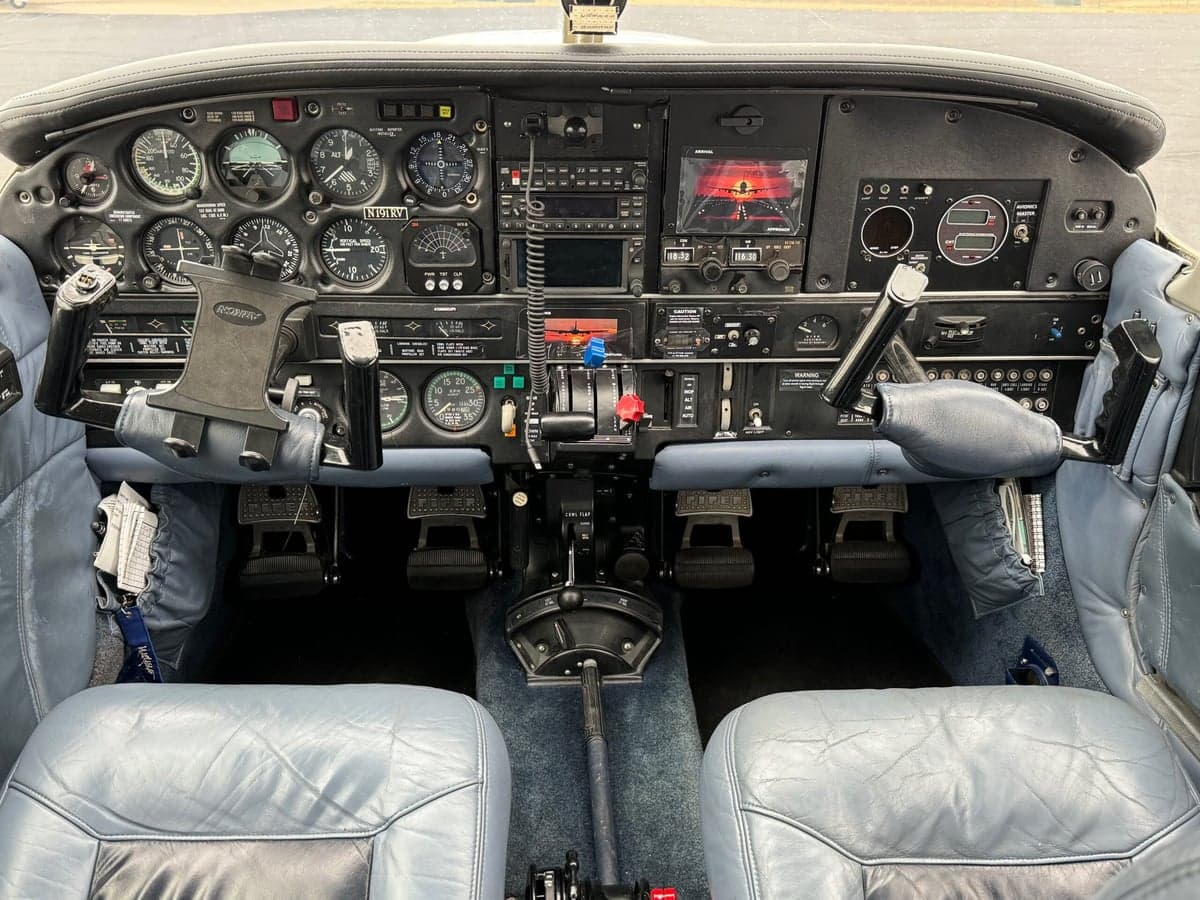 View of the aircraft cockpit with a detailed instrument panel and blue leather seats.