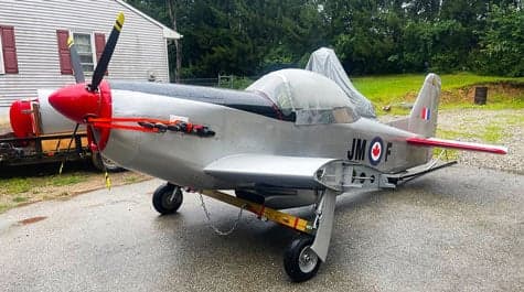 A silver and red aircraft with Canadian markings is parked on a trailer.