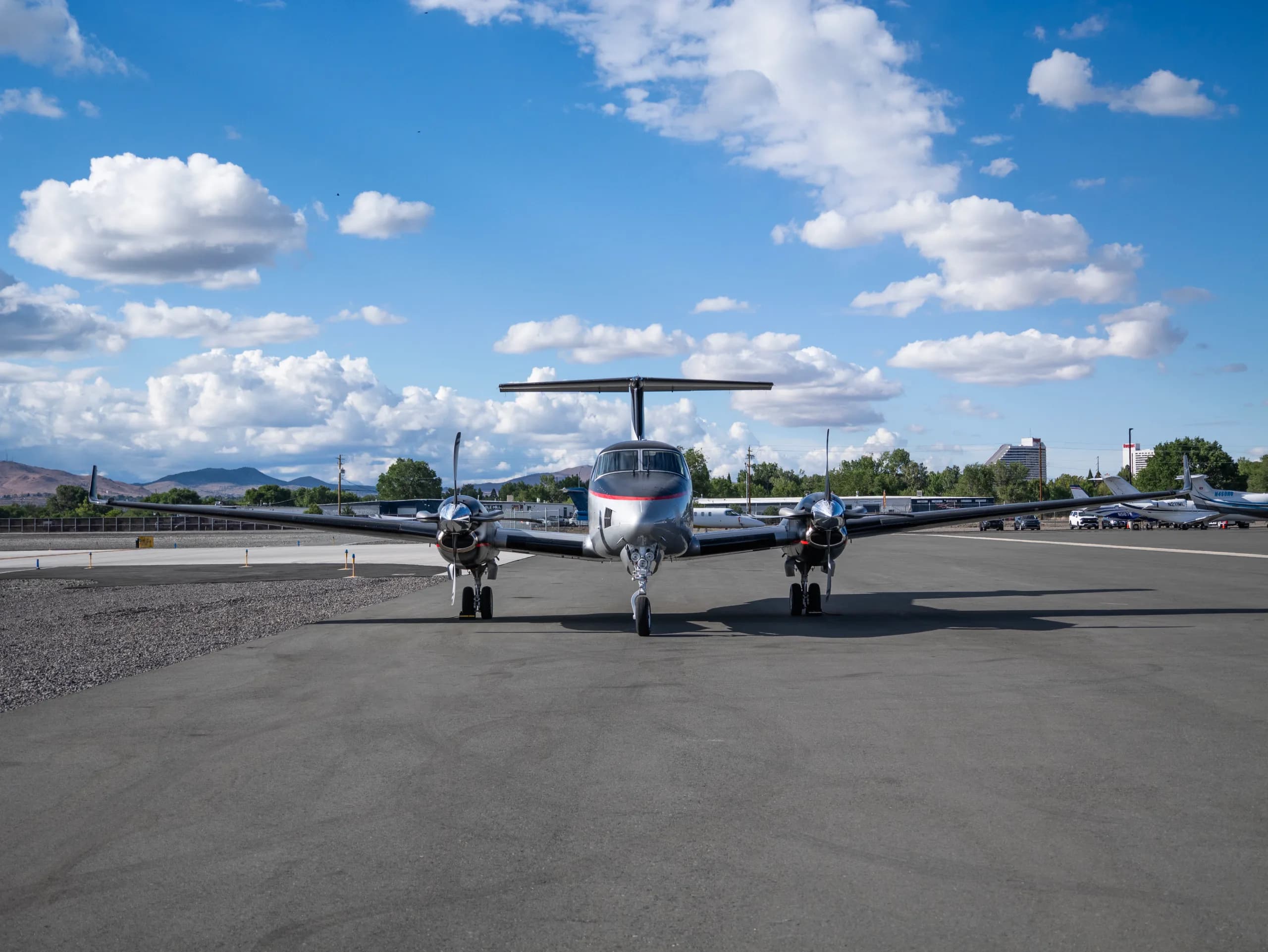 A head-on view of the silver and black twin-turboprop aircraft with red accents parked on an airport tarmac.