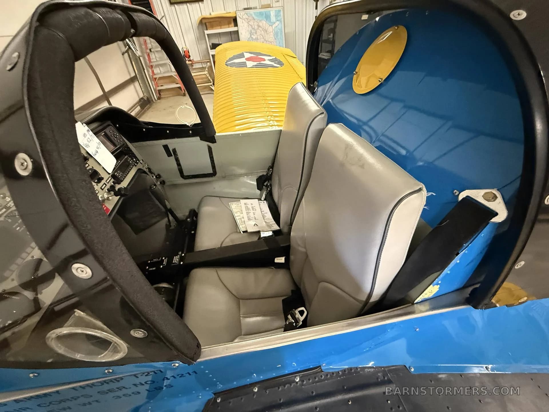 Interior view of the aircraft cabin showing two grey seats and part of the instrument panel.
