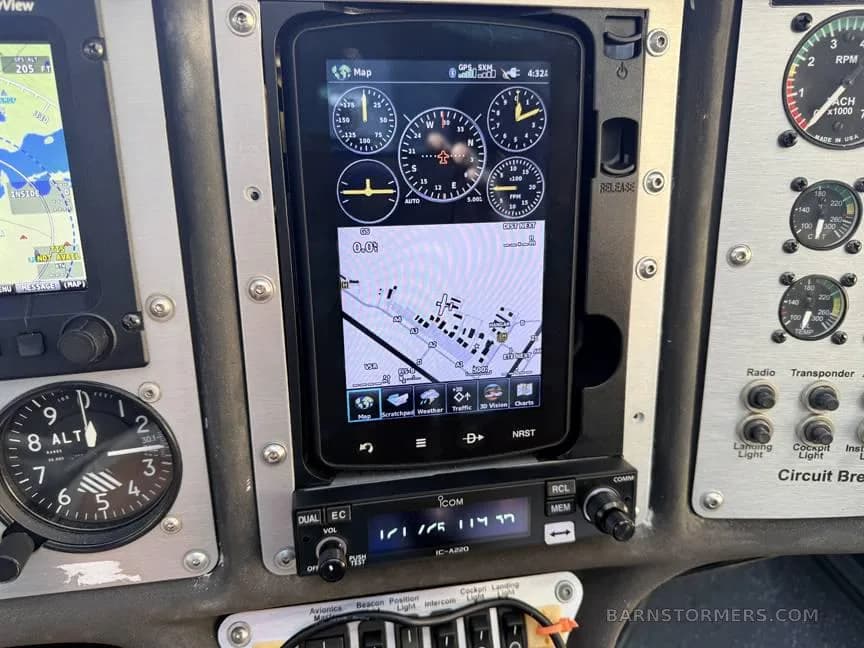 A close-up of the center console in a light sport aircraft cockpit, showing a GPS map display and an ICOM radio.