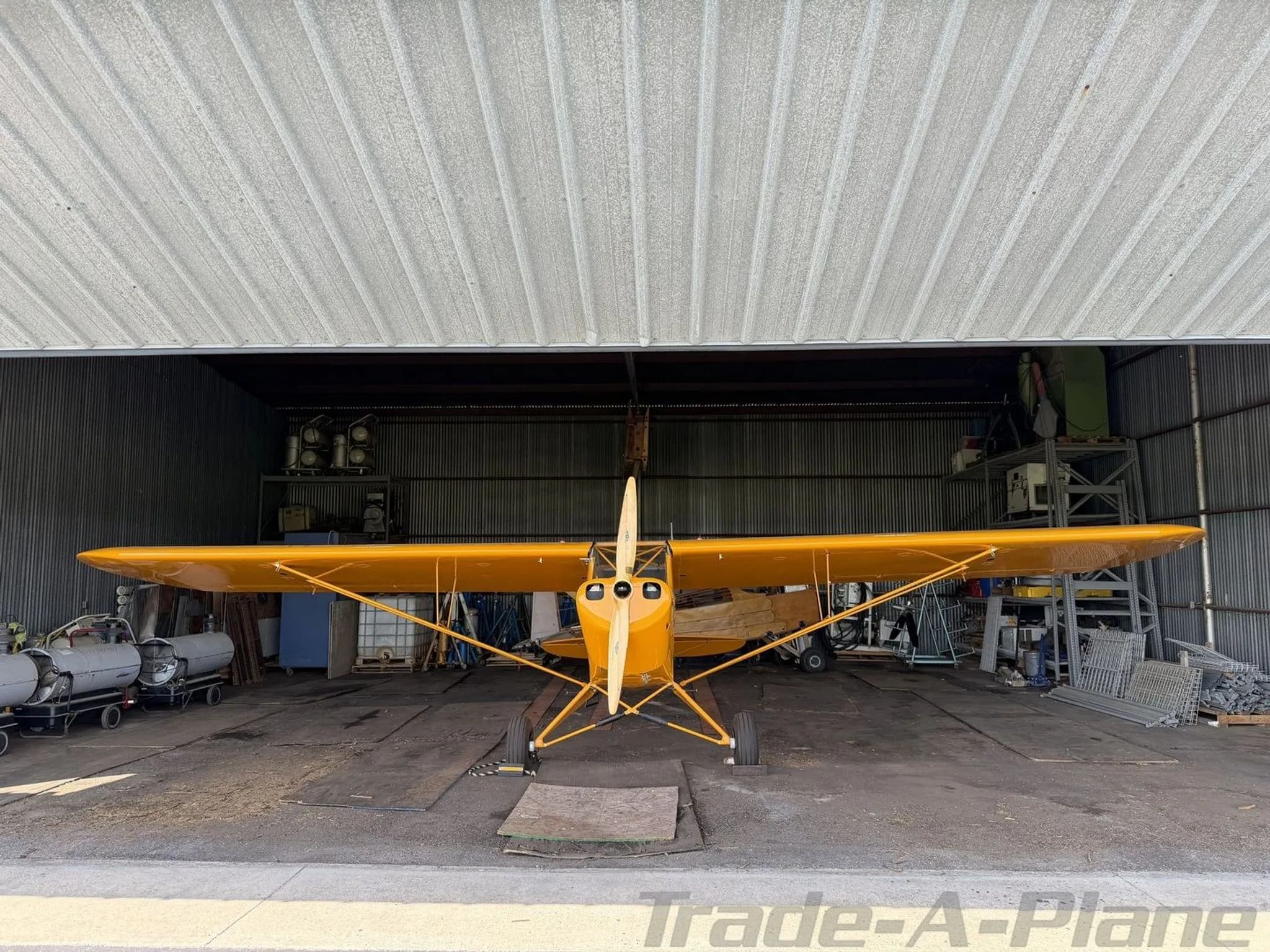 Front view of a yellow American Legend Cub aircraft inside a hangar.