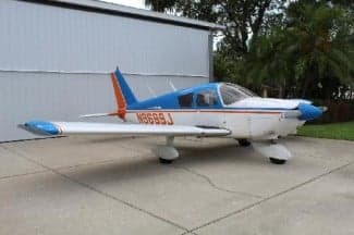 Side view of a blue and white Piper Archer aircraft with tail number N9699J parked on a concrete surface.