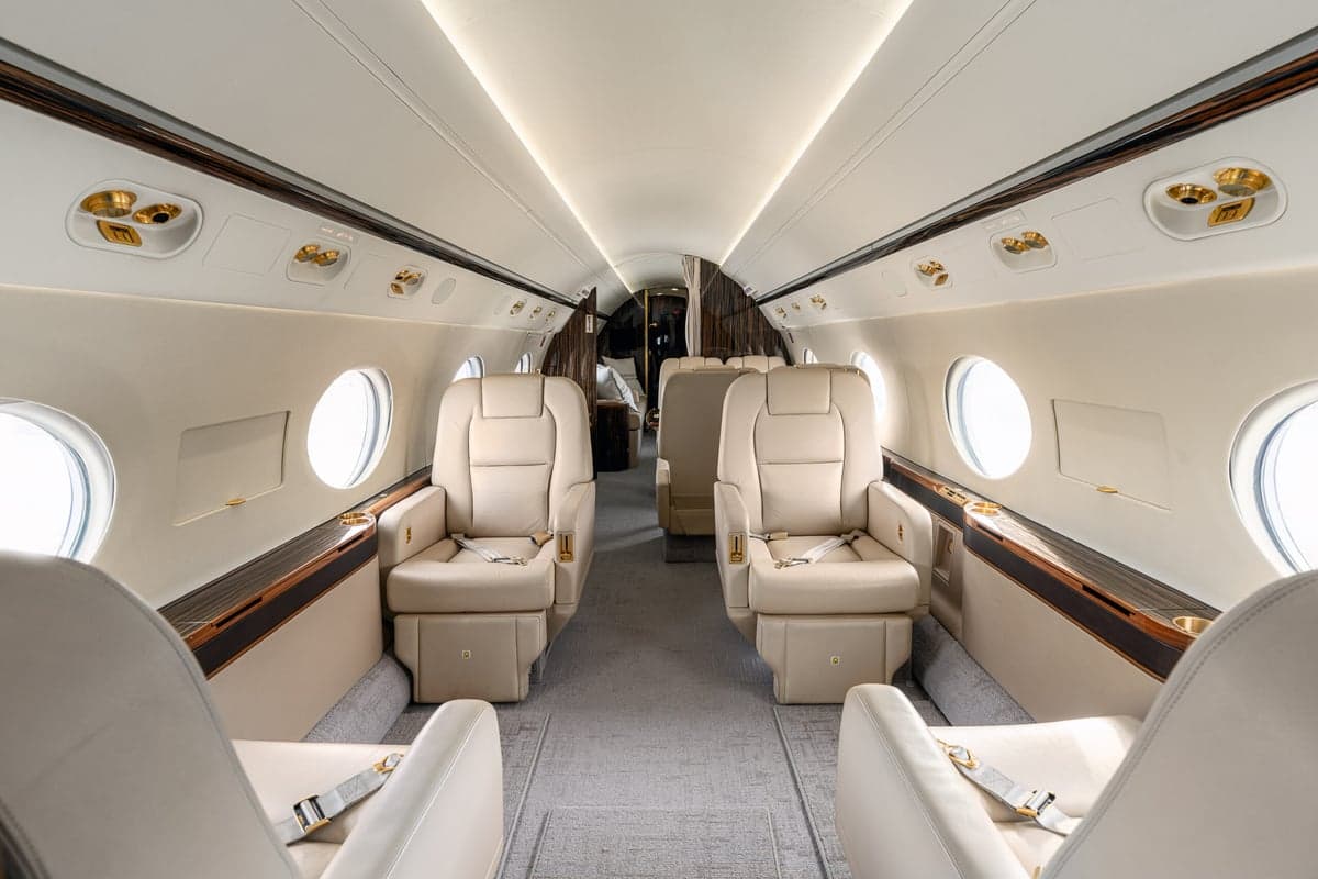 The interior of the aircraft features cream-colored leather seats and wood grain finishings.