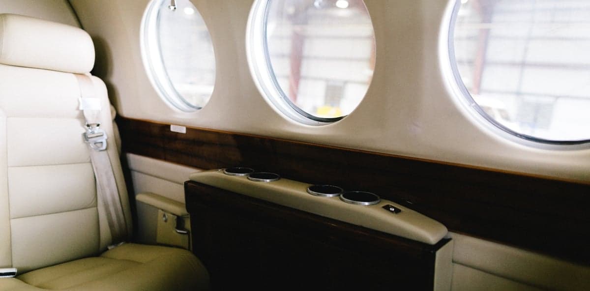 Close-up of the aircraft's interior with a leather seat, side table, and windows.