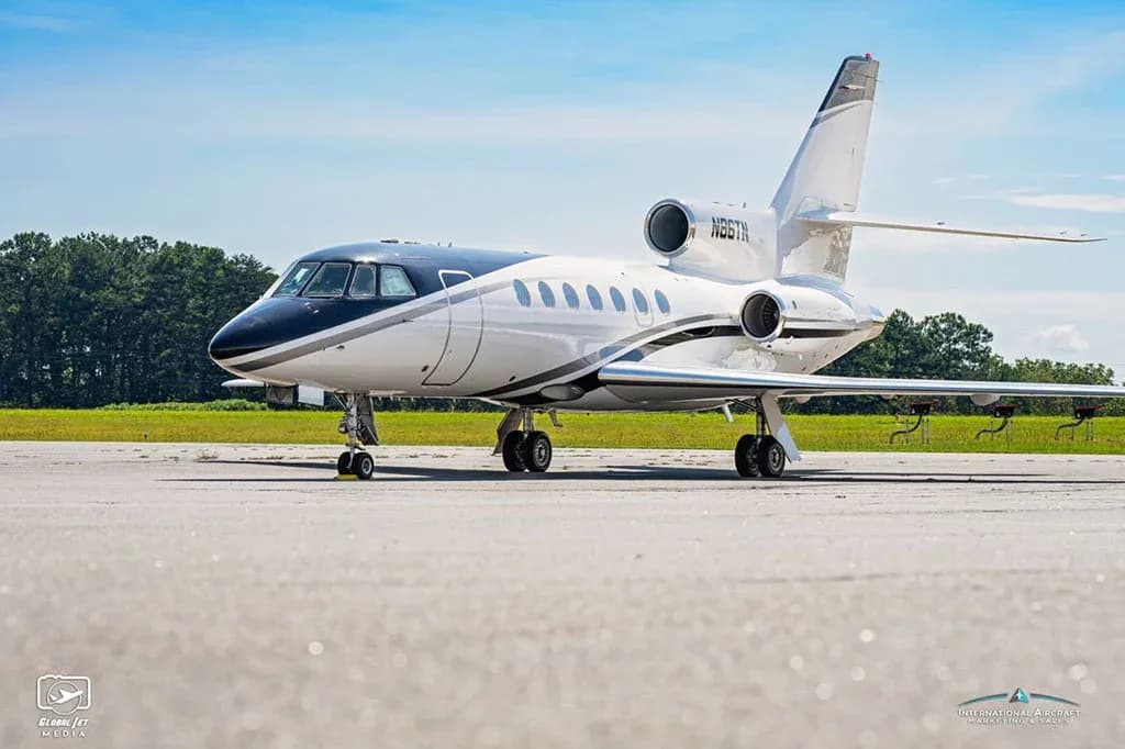 A Dassault Falcon 900EX business jet, registration N86TN, parked on an airfield with a black nose and white fuselage.