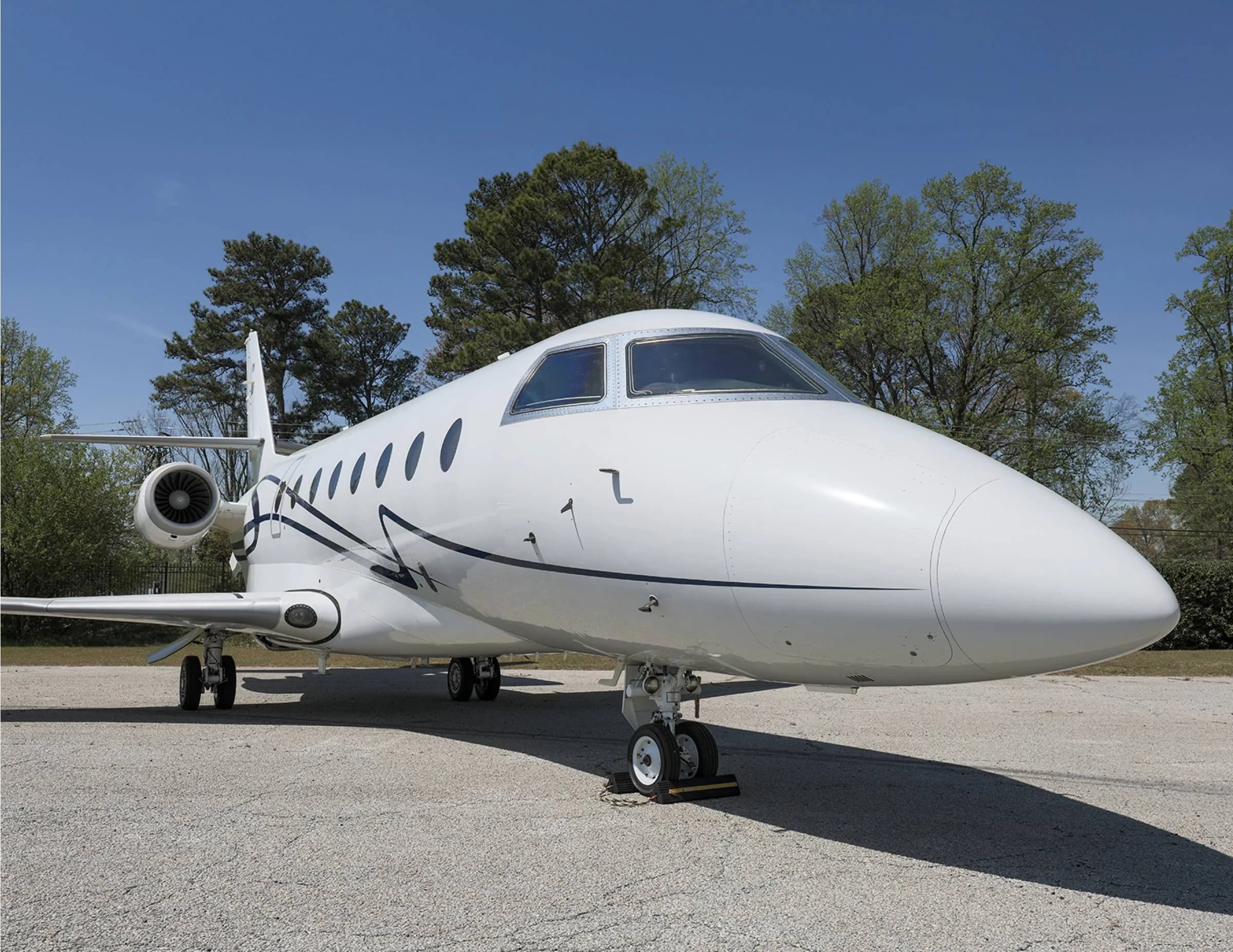 Close up of the nose of a white aircraft with blue accents parked on the tarmac.