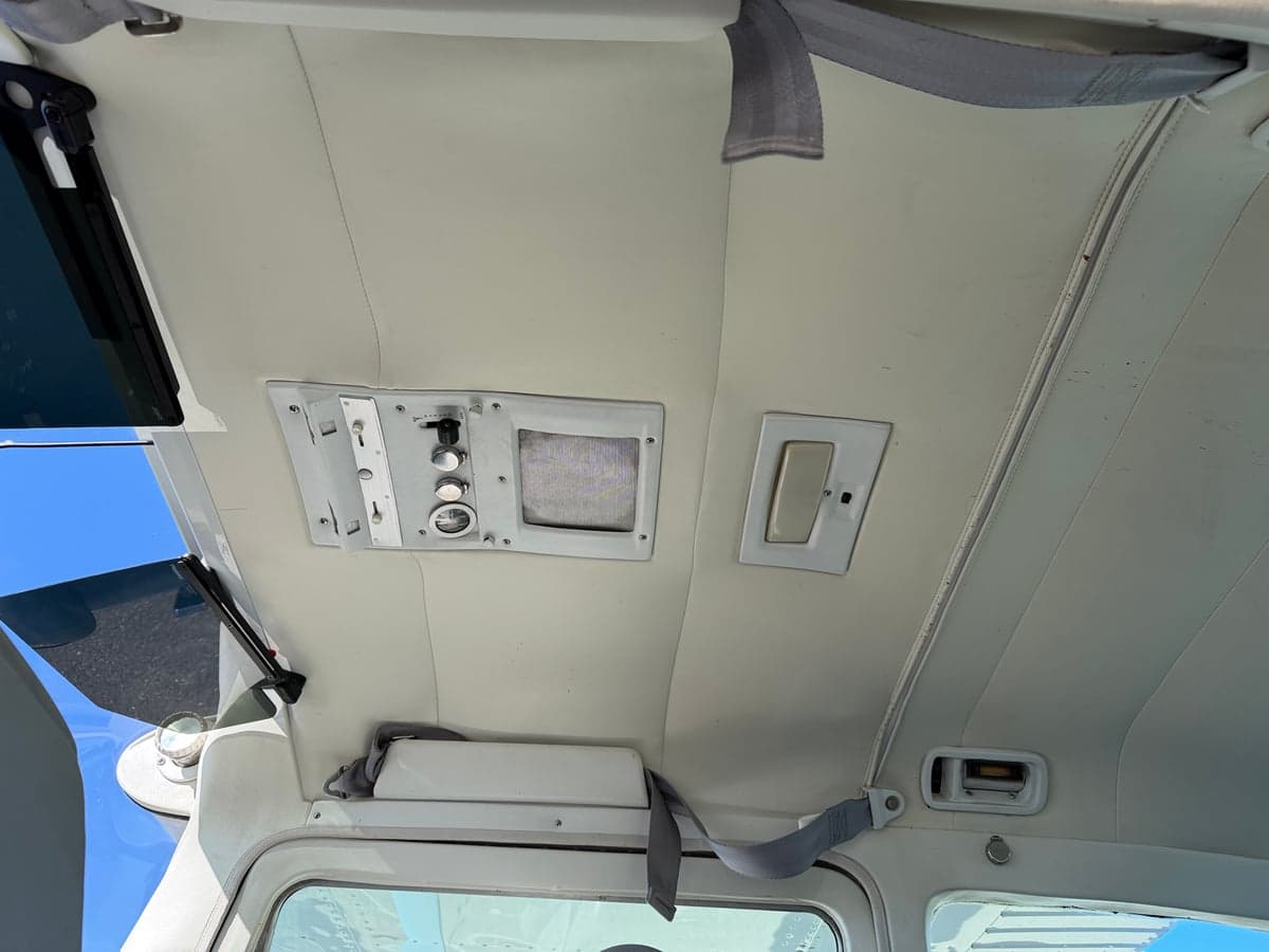 The aircraft's interior features a white ceiling with various controls and vents.