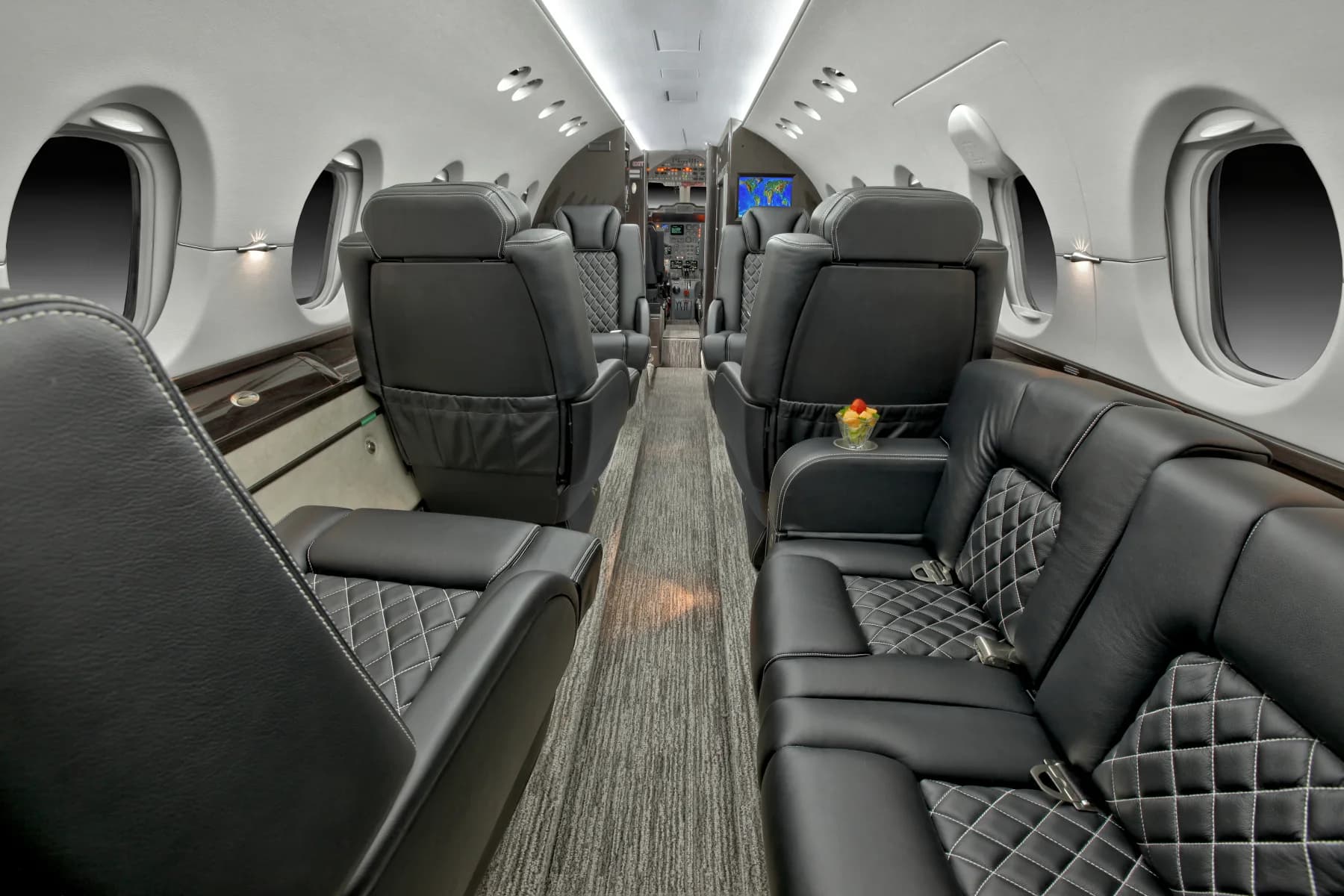 Interior view of the aircraft cabin with black leather seats and a gray carpet.