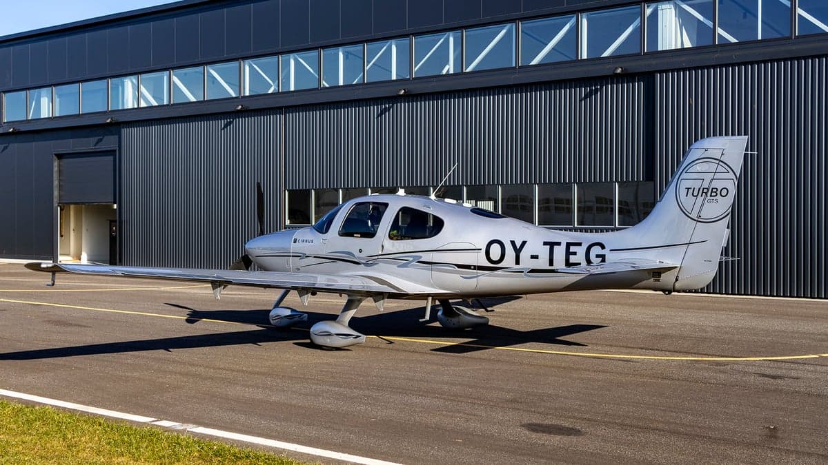 Side view of the silver Cirrus OY-TEG on the tarmac.