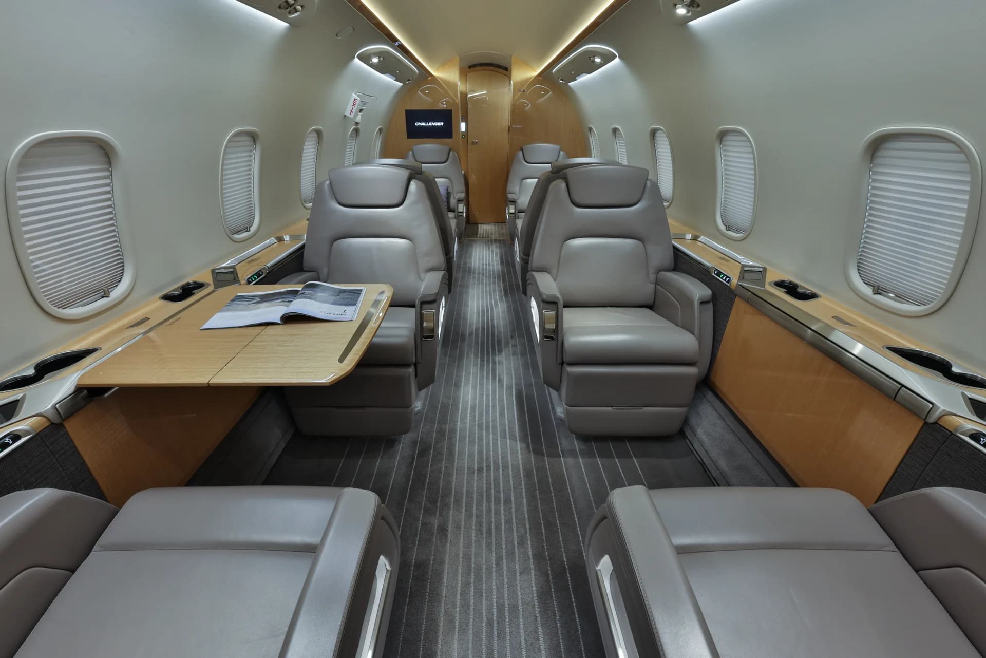 The interior of a Challenger aircraft with leather seats and a table.