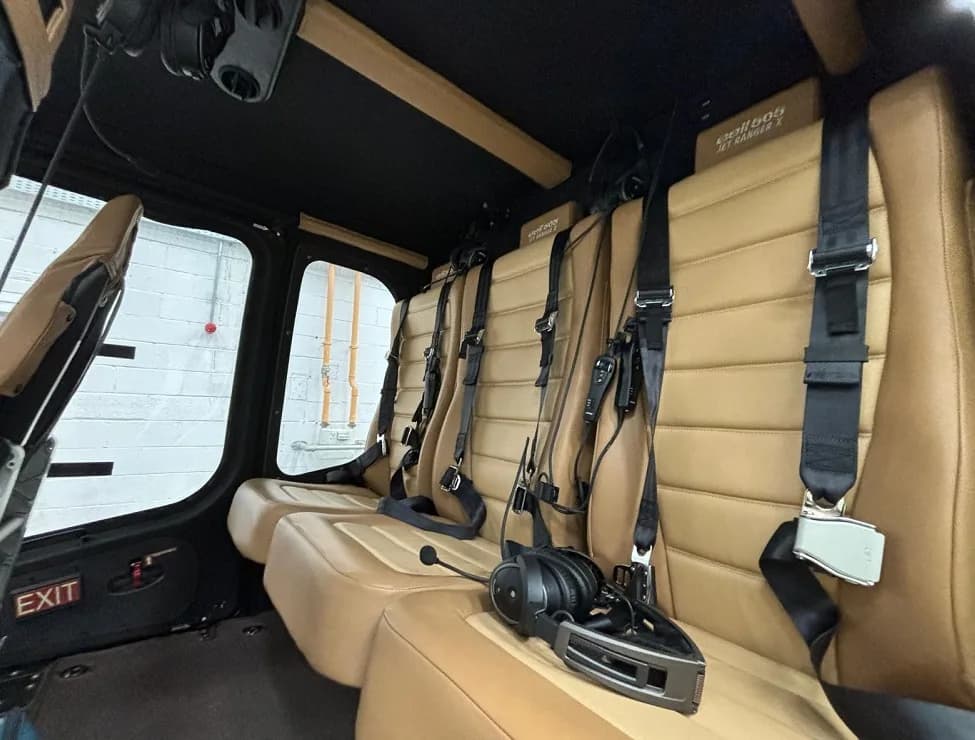 Interior view of the helicopter cabin with tan leather seats and headsets.
