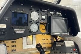 The cockpit of an aircraft with a black instrument panel and various gauges and screens.