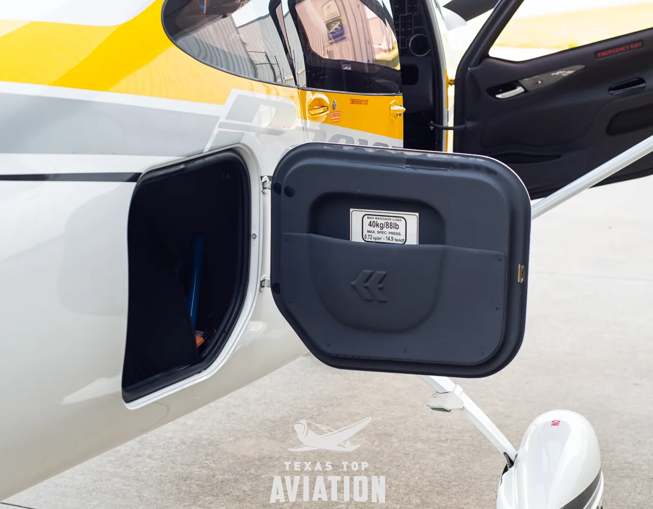 A close-up of an open exterior compartment on the side of a white aircraft fuselage.