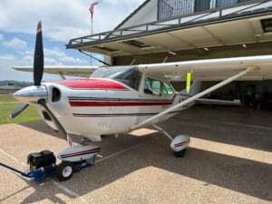 Side view of a Cessna 182 Skylane, registration N71699, parked under a covered area with a tow bar attached.