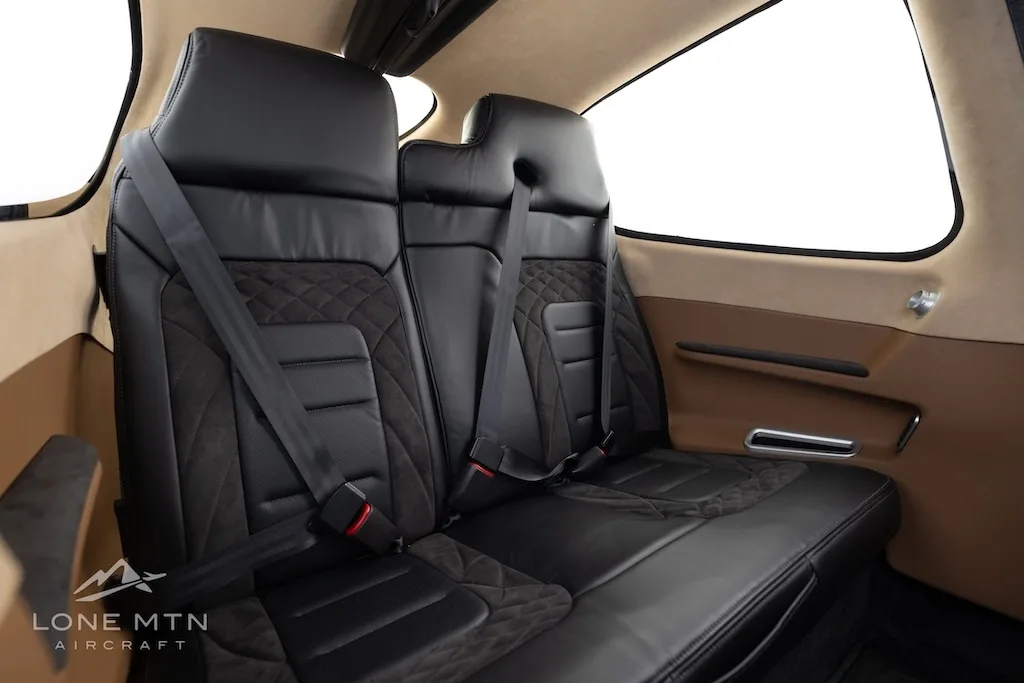 A view of the black leather rear seats with quilted patterns and tan side panels inside the aircraft cabin.