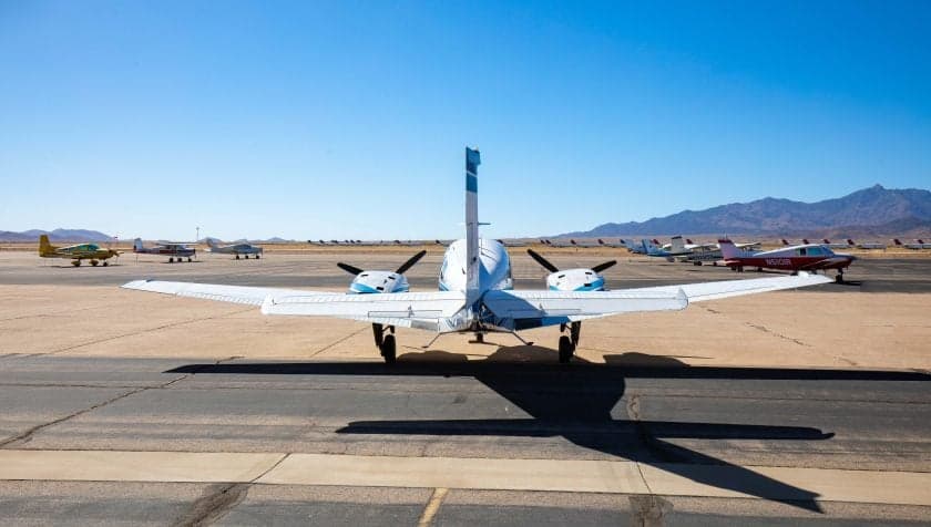 Rear view of a Beechcraft Baron on the tarmac with other aircraft in the background.