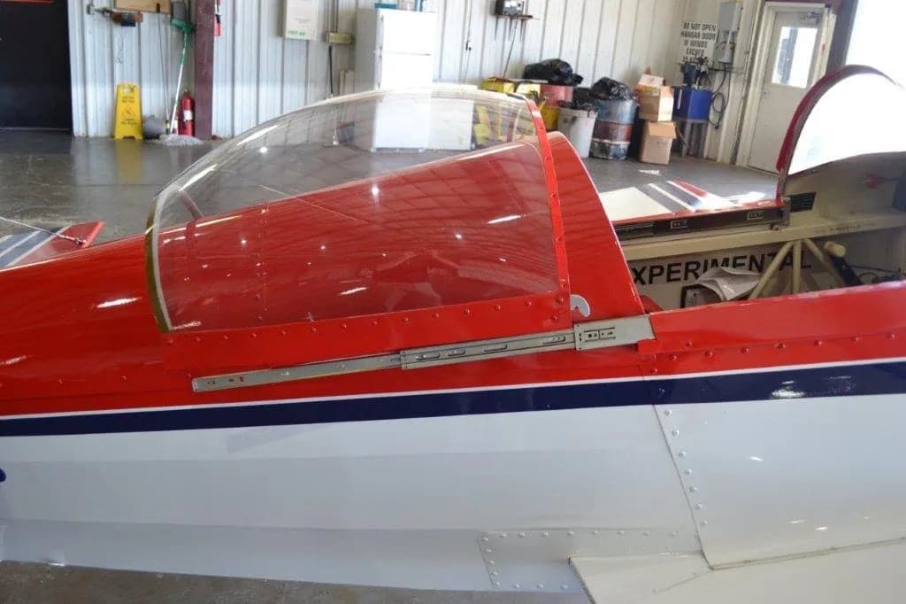 Close up of the canopy of a red and white aircraft with stars on the tail and wings.