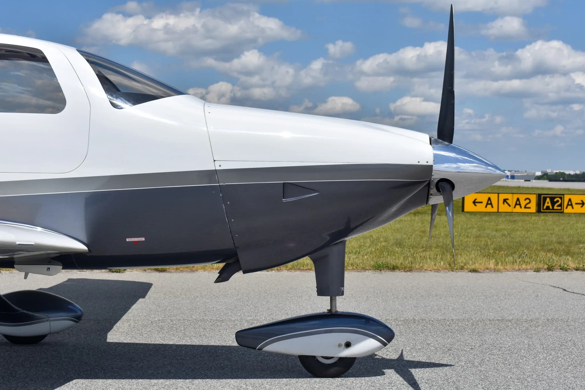 A close-up view of the nose and propeller of a white and dark grey Cessna TTx (Corvalis 400) aircraft.