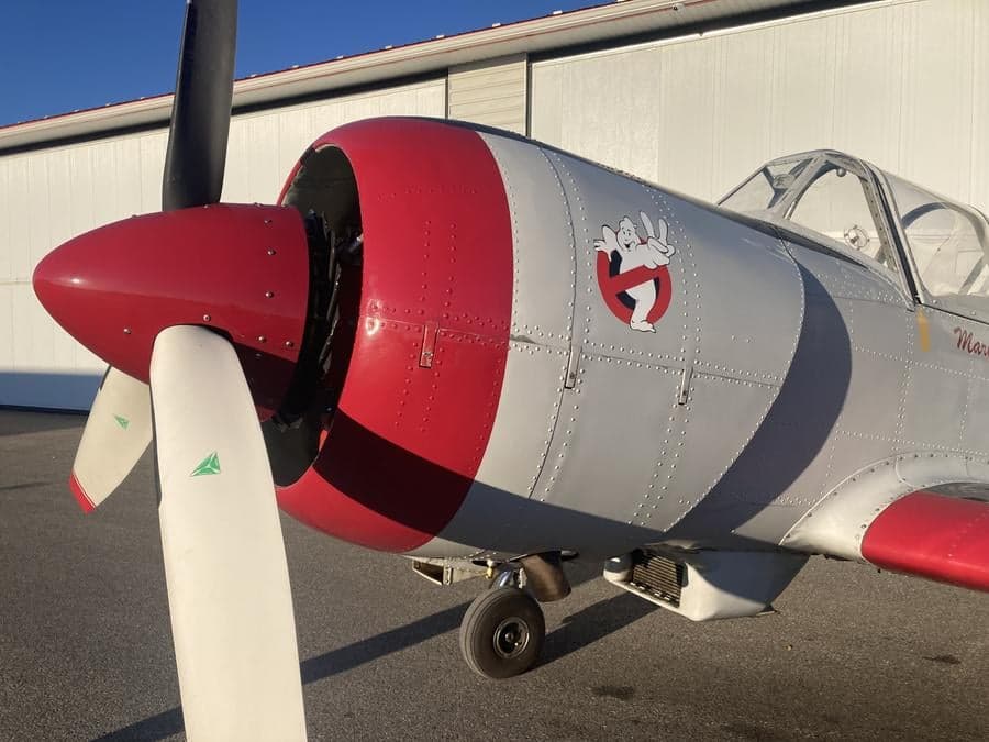 Close-up of the nose and propeller of a Yak-52TW aircraft with a red spinner.