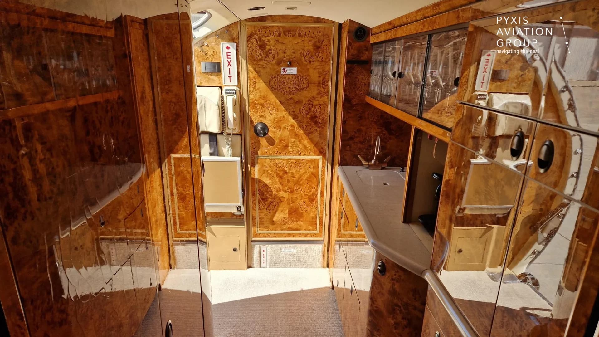 The aircraft's galley area with a sink, storage cabinets, and wood paneling.
