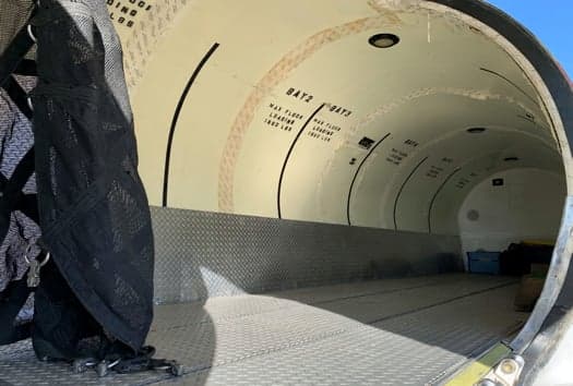 View inside the cargo area of an aircraft, showing the floor and wall markings.