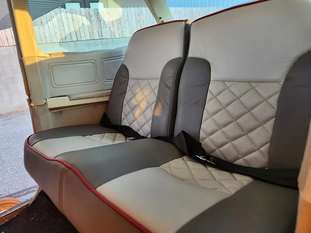 The rear cabin seats of the aircraft, upholstered in gray and white with a quilted pattern and red piping.