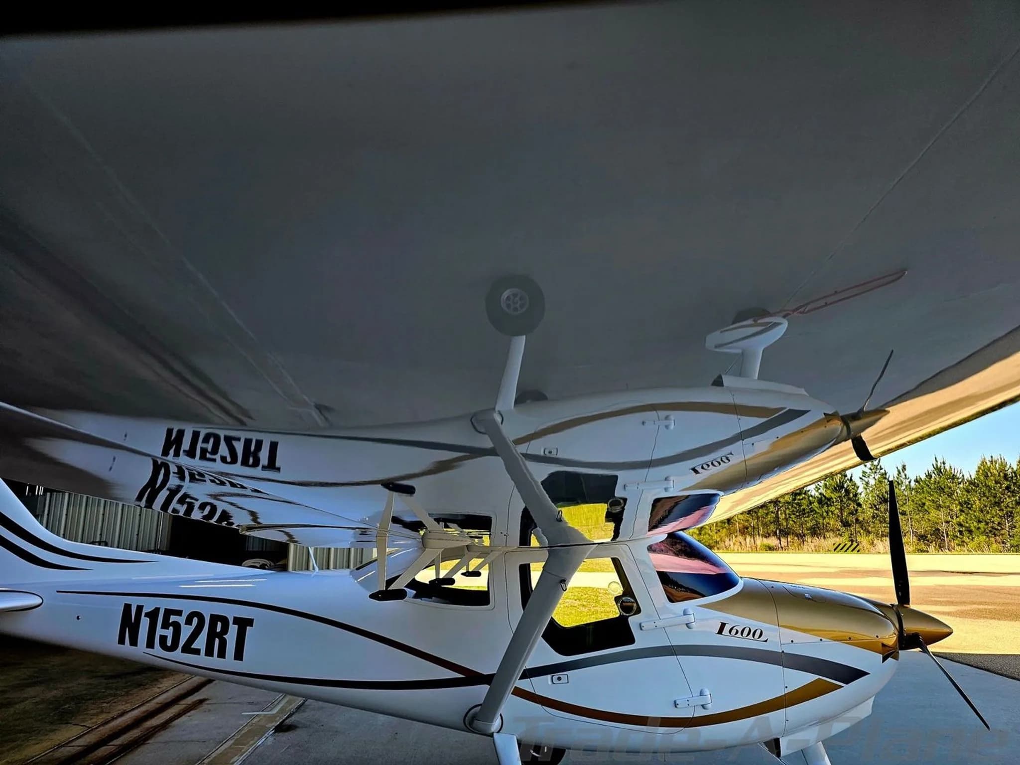 The I600 aircraft (N152RT) parked with its reflection visible on the underside of its wing.