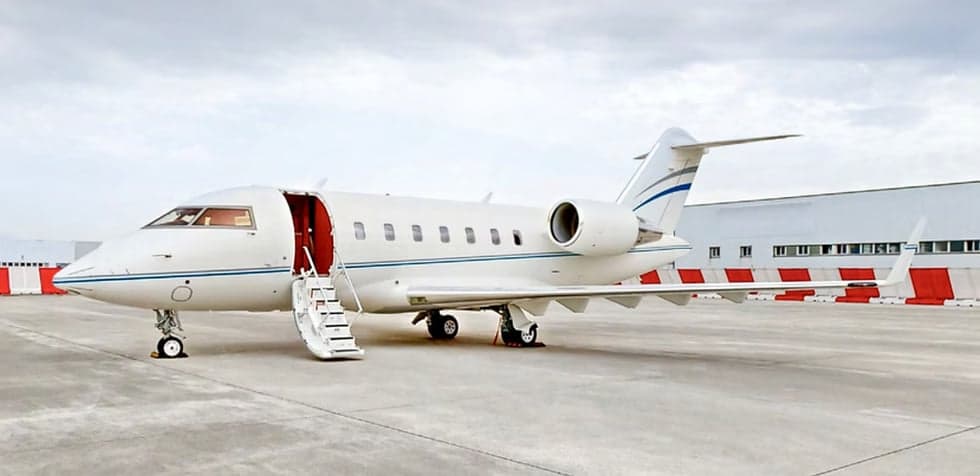 A Challenger aircraft is parked on the tarmac with the stairs down.