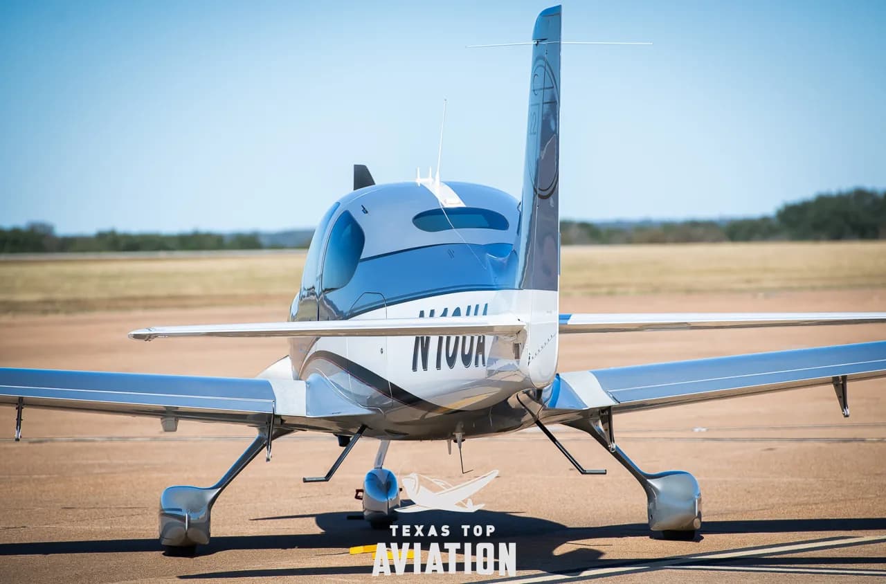 Rear view of a silver and white Cirrus SR22 aircraft (N10UA) parked on an airfield.