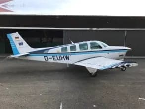 Side view of the D-EUHW aircraft parked in front of a hangar.